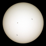 Silhouettes of the International Space Station in two different positions in front of the Sun
